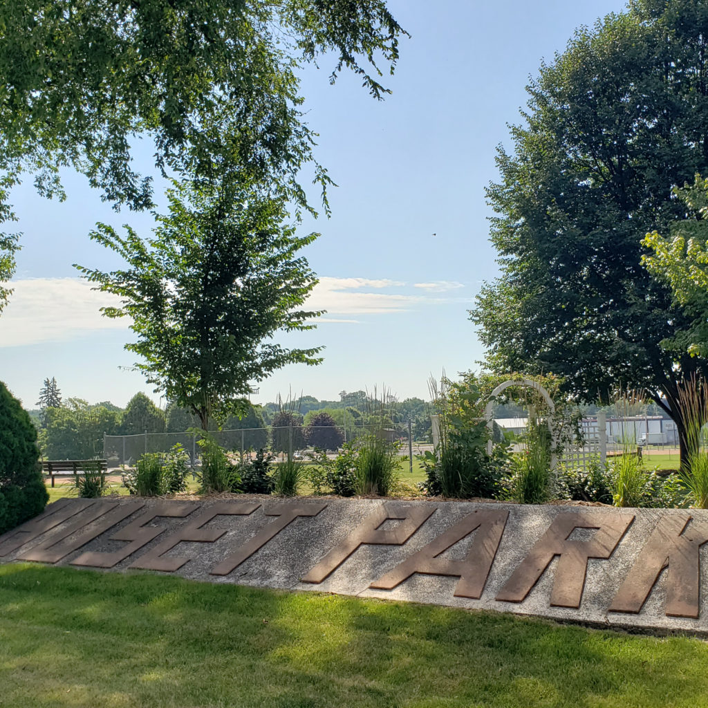 Monument letters on an embankment spell out Huset Park placard as seen from Mill Street in Columbia Heights, MN